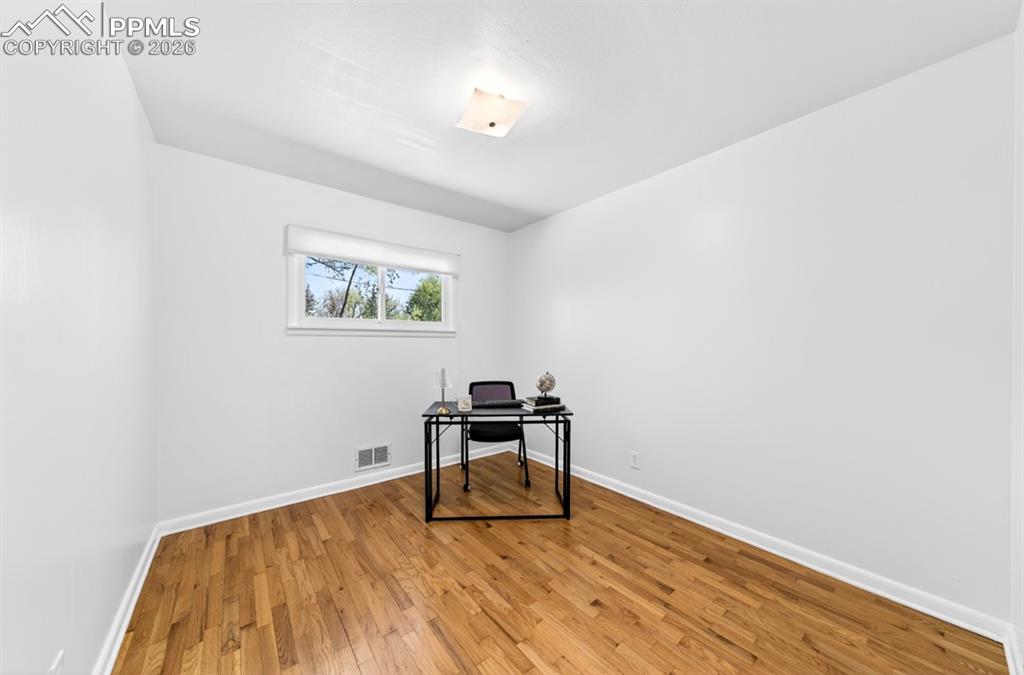 Image 34 of 46: Room featuring hardwood flooring, white walls, and two windows with roller 