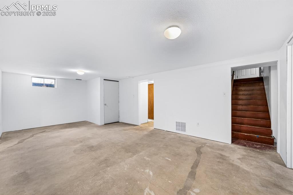 Image 38 of 46: Spacious interior room with white painted walls, a textured ceiling, and a 