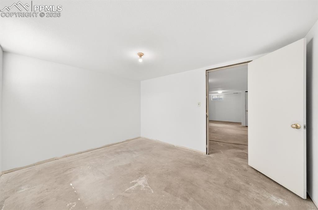 Image 41 of 46: Unfinished basement space featuring exposed concrete walls and ceiling