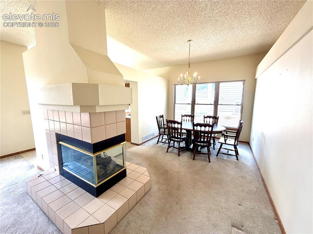 Image 13 of 50: Two-sided fireplace with a tiled hearth and a custom-built hood