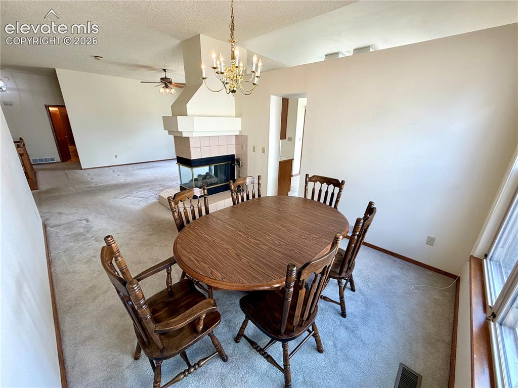 Image 14 of 50: Open-concept living space featuring a central fireplace with a glass-enclos