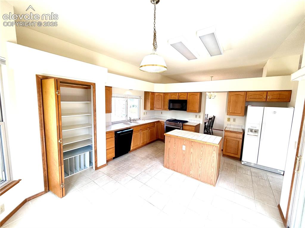Image 17 of 50: Kitchen featuring tile flooring, wood cabinetry, a central island, and whit