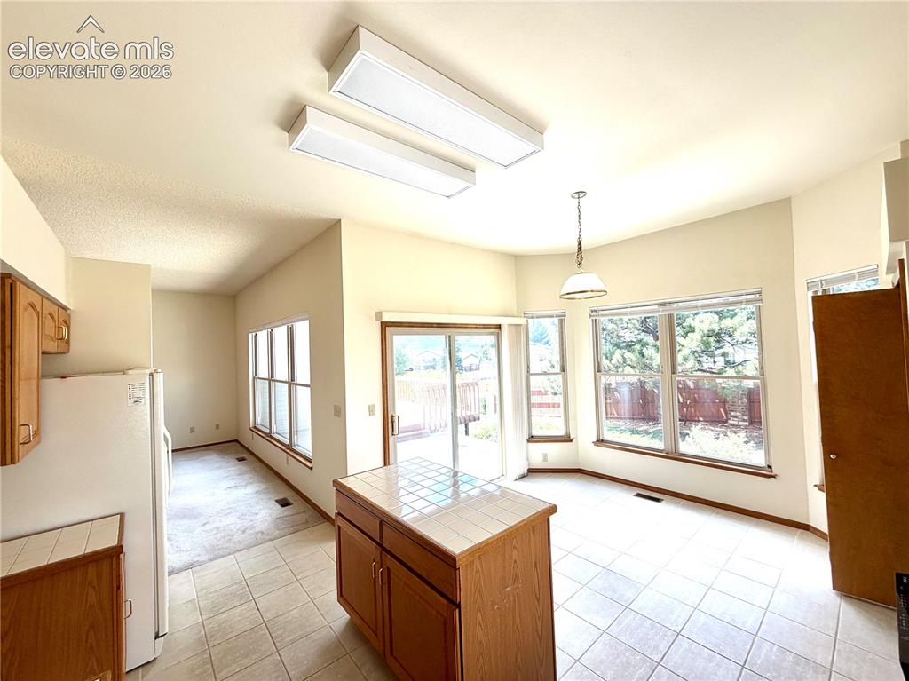 Image 18 of 50: Open-concept kitchen and dining area featuring tile flooring, a central isl