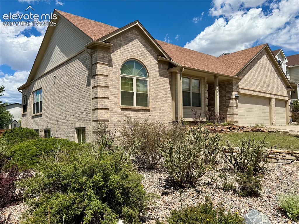Image 2 of 50: Brick exterior residence featuring a prominent arched window, two-car garag