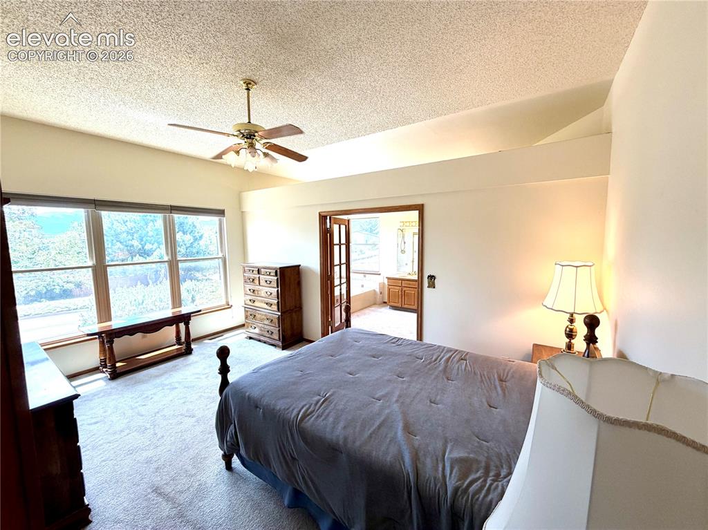 Image 20 of 50: Spacious bedroom featuring large windows, vaulted ceilings with a ceiling f