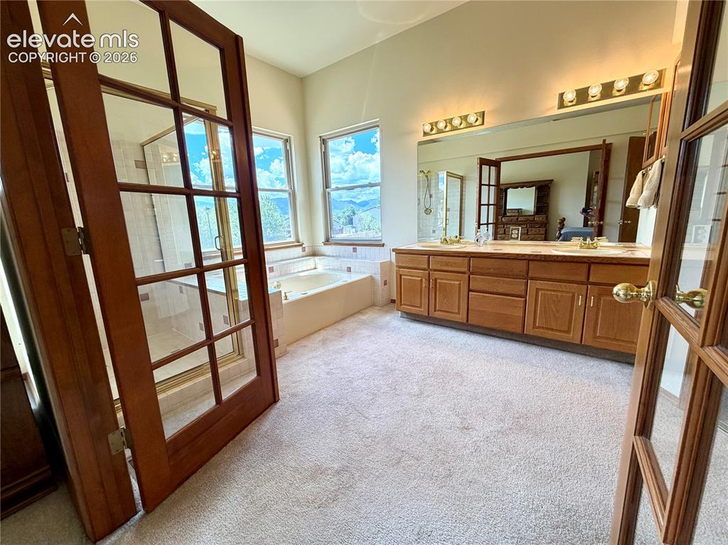 Image 22 of 50: Spacious bathroom featuring a dual vanity with wood cabinetry, a built-in j