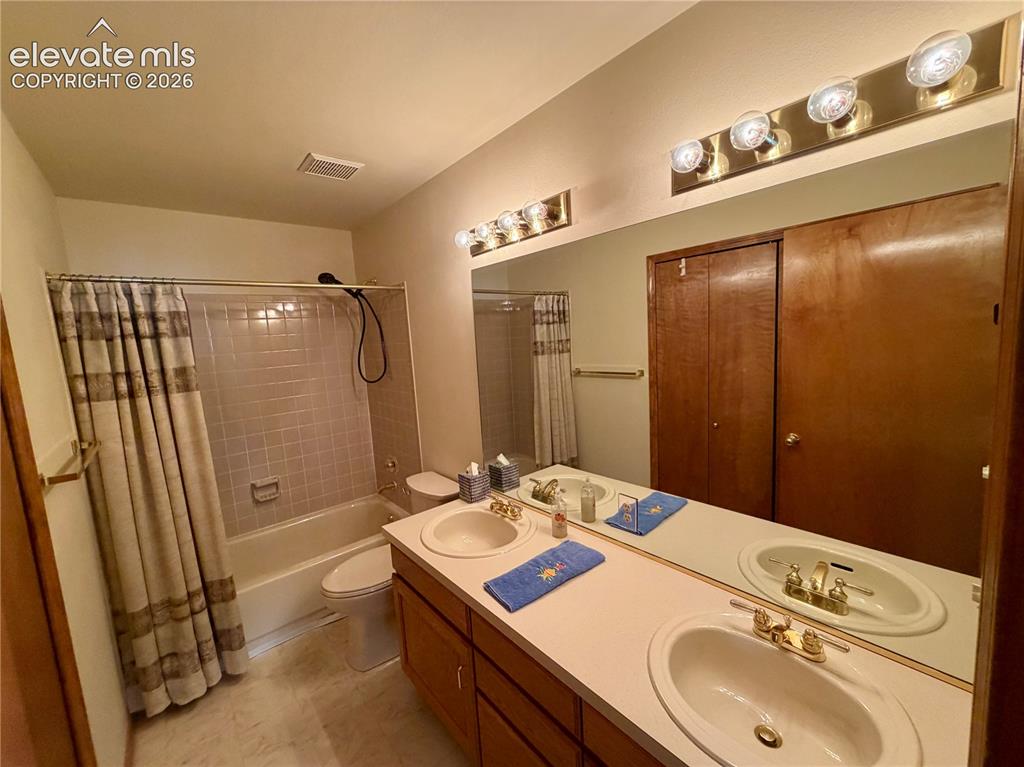 Image 27 of 50: Double vanity featuring white oval sinks with gold-toned fixtures and a lig