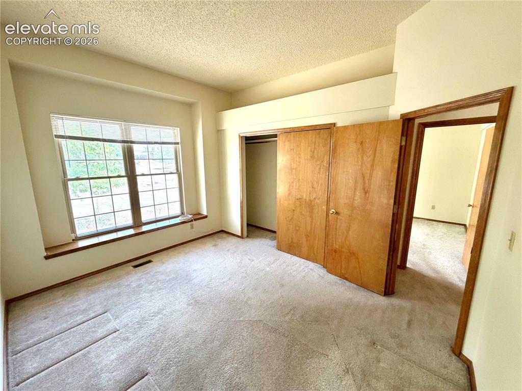 Image 31 of 50: Carpeted interior space featuring a large window with white grilles and a w