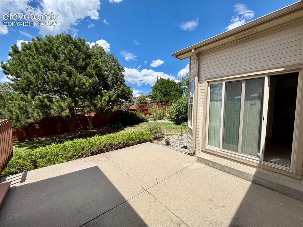 Image 36 of 50: Concrete patio featuring a sliding glass door and tan siding
