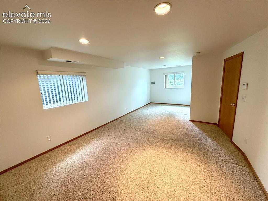 Image 37 of 50: Spacious room featuring neutral carpeting, white walls, recessed lighting,