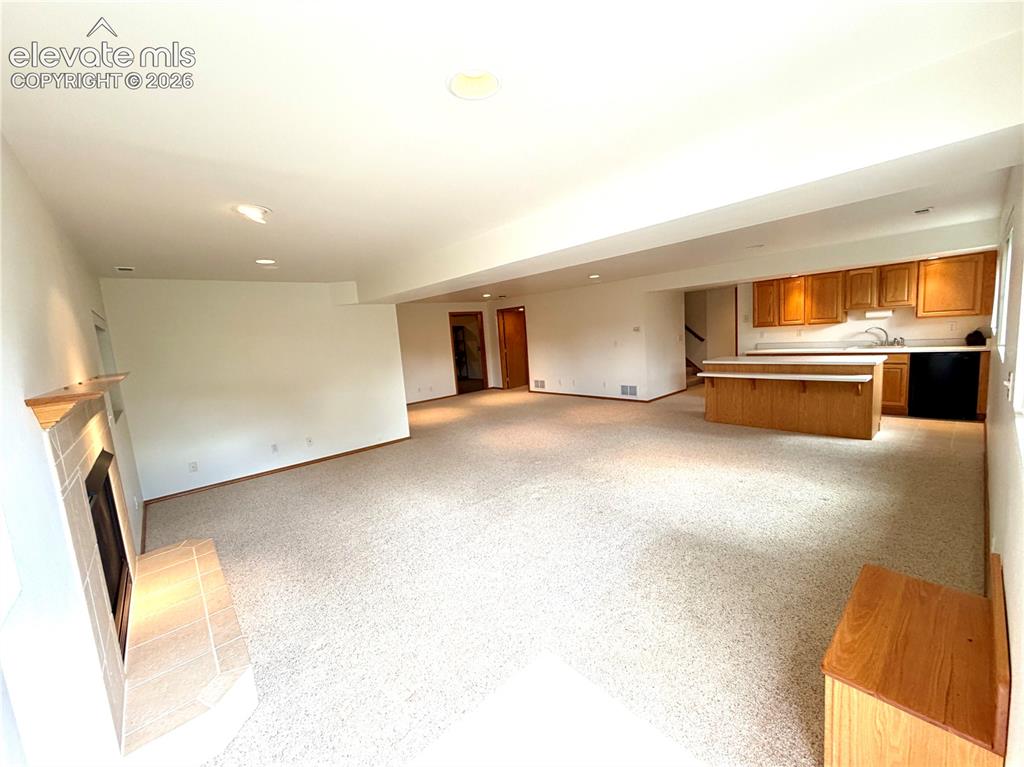 Image 44 of 50: Spacious open-concept living area featuring light-colored carpeting, a tile