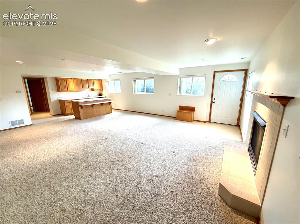 Image 45 of 50: Spacious living area featuring a corner fireplace with a tiled surround and