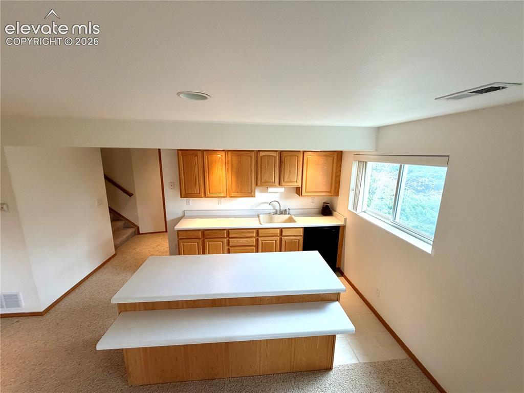 Image 46 of 50: Basement Kitchen area featuring oak cabinetry, a two-tier island with white