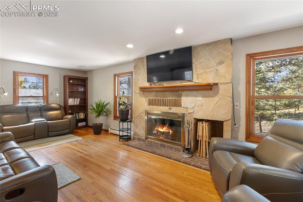 Image 12 of 50: Main level living room with wood burning fireplace, hardwood floors, and fu