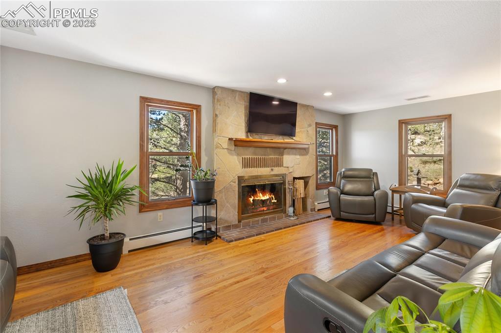 Image 13 of 50: Main level living room with hardwood flooring, wood burning fireplace and f