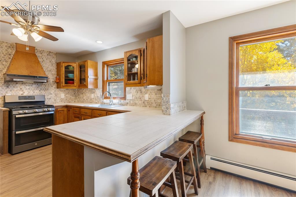 Image 16 of 50: Main level kitchen with breakfast bar, updated countertops, backsplash, sta