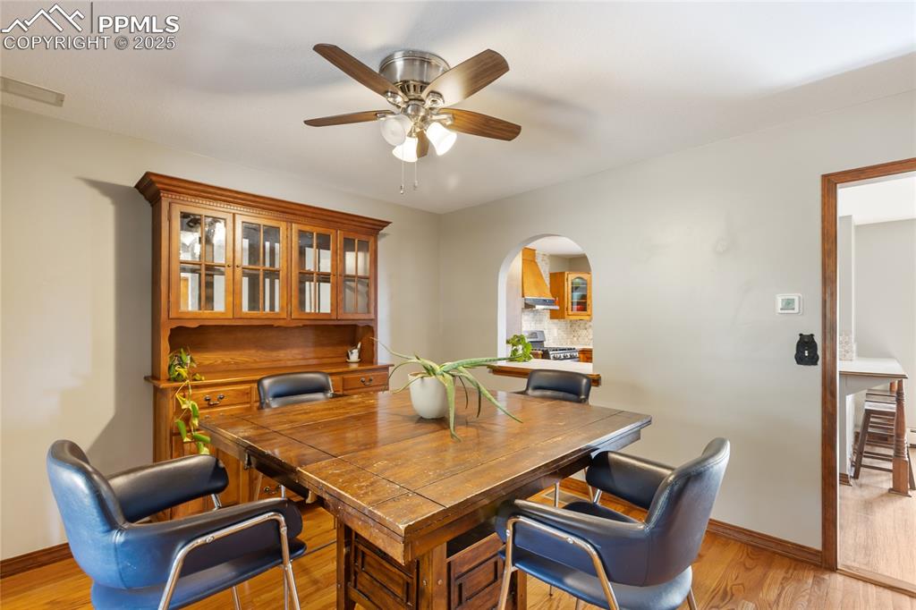Image 20 of 50: Formal dining room with hardwood flooring, arched opening into kitchen