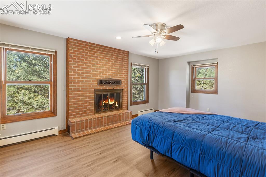 Image 23 of 50: Upper level bedroom with woodburning fireplace, LVP flooring and ensuite