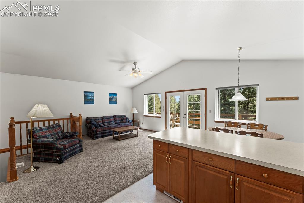 Image 14 of 36: Living area featuring a ceiling fan, vaulted ceiling, and light carpet