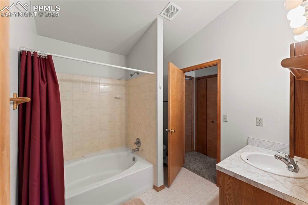 Image 20 of 36: Bathroom featuring shower / bath combo with shower curtain, vanity