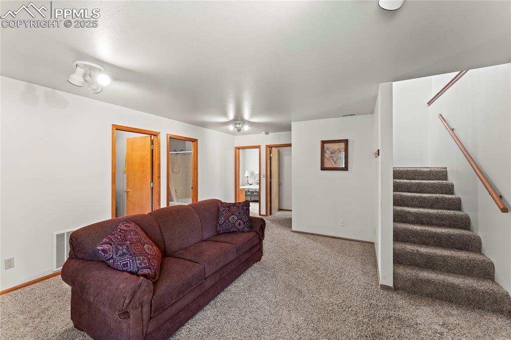 Image 23 of 36: Living area featuring light colored carpet and stairway