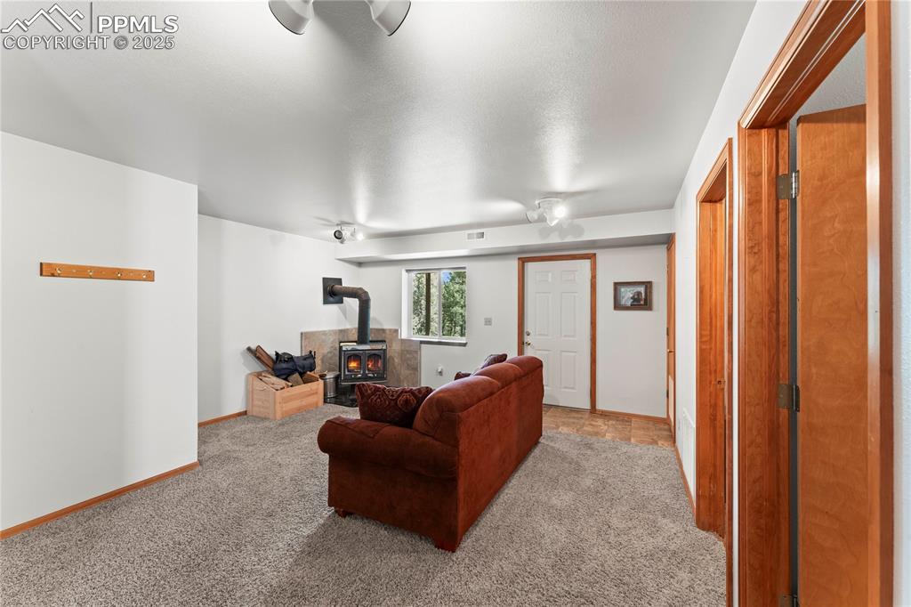 Image 24 of 36: Carpeted living area featuring a wood stove and walk out exit to backyard