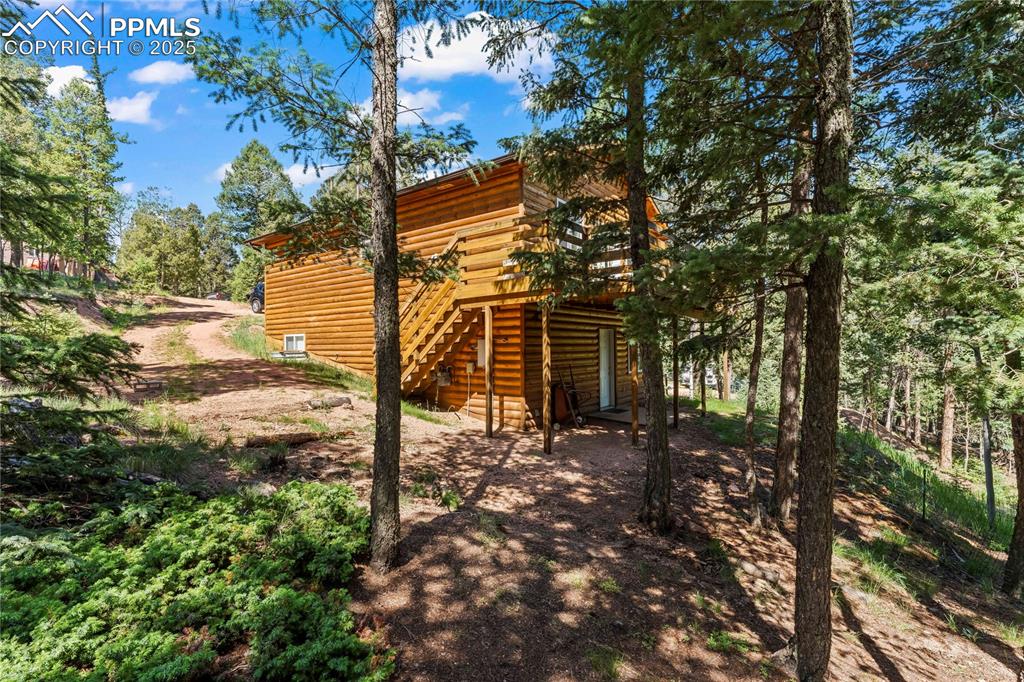 Image 4 of 36: View of property exterior with a wooden deck, stairway, and log siding