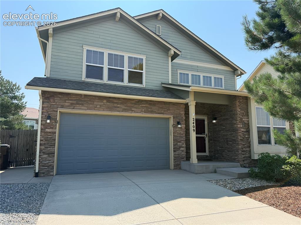 Caption: Two-story home featuring a stone and siding exterior with a double-car garage, concrete driveway, an