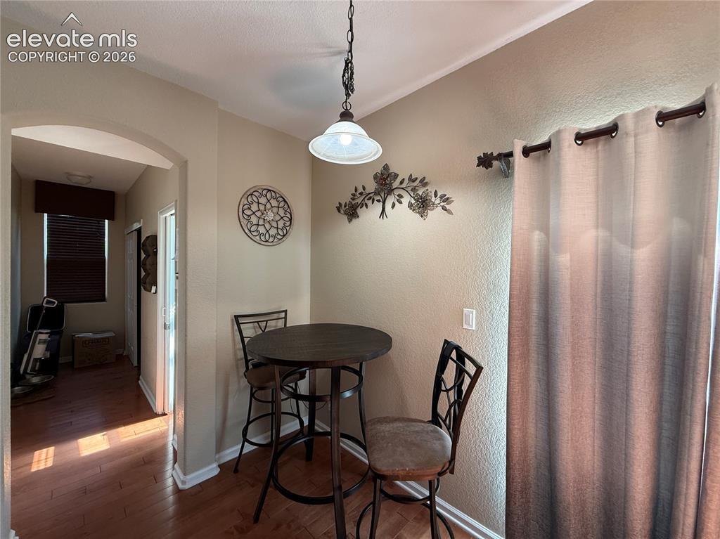 Image 10 of 27: Wood-finish flooring throughout, arched entryway, and a hanging pendant lig