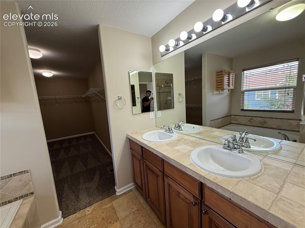 Image 14 of 28: Dual undermount sinks with chrome fixtures, tile countertop, extended vanit