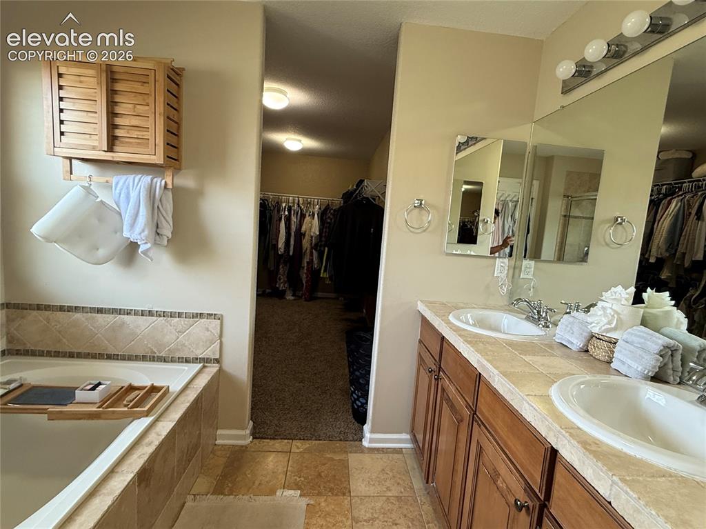Image 15 of 27: Spa-inspired master bathroom featuring dual vanities with wood cabinetry, m