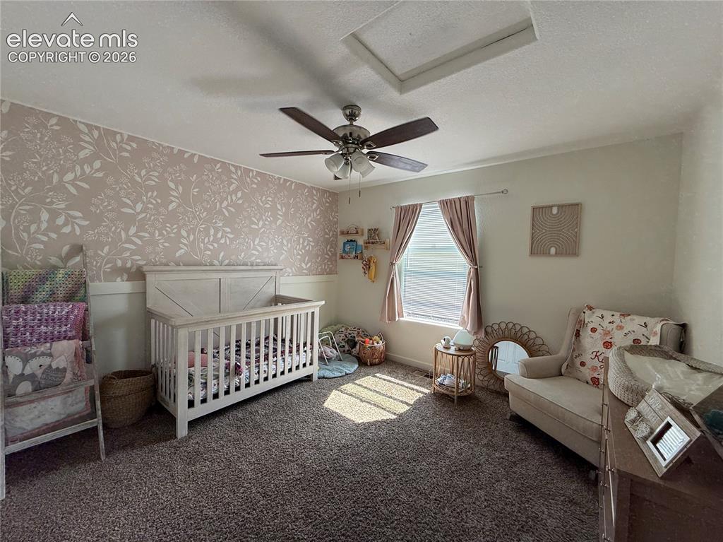 Image 18 of 27: Bright nursery with carpet flooring, ceiling fan with integrated lighting,