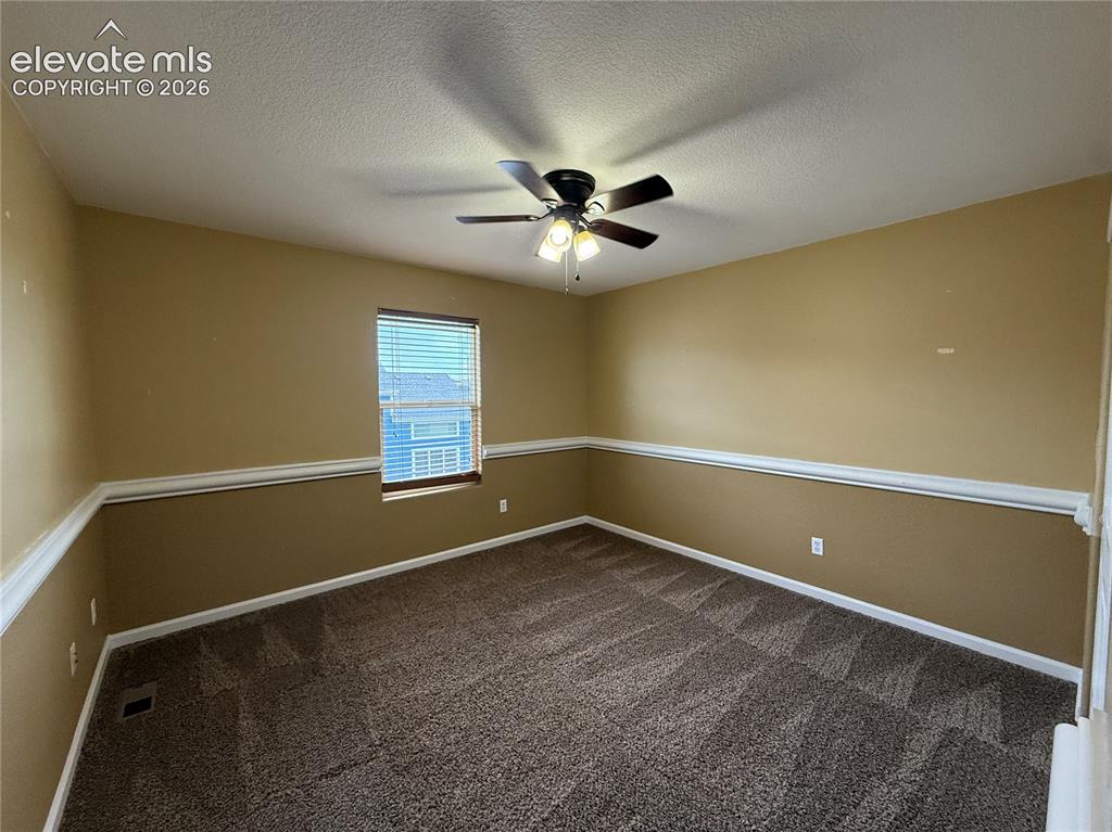 Image 19 of 28: Textured carpeting, accent wall molding, ceiling fan with light fixture, an