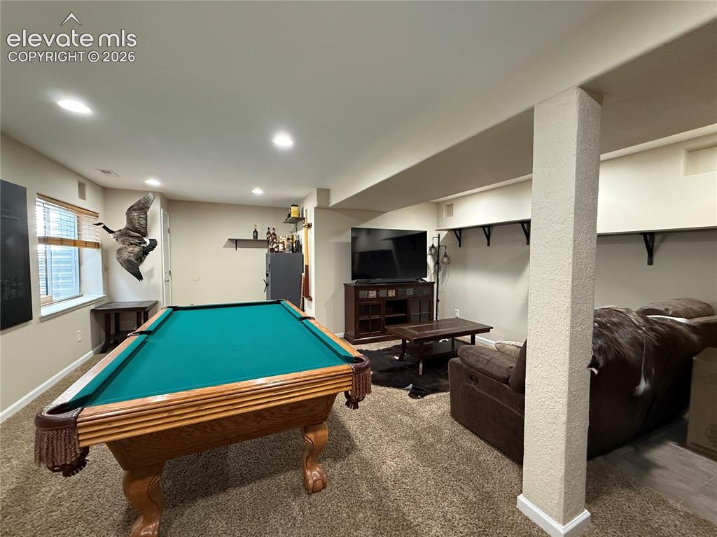 Image 22 of 27: Carpeted recreation room with recessed lighting and a window featuring hori