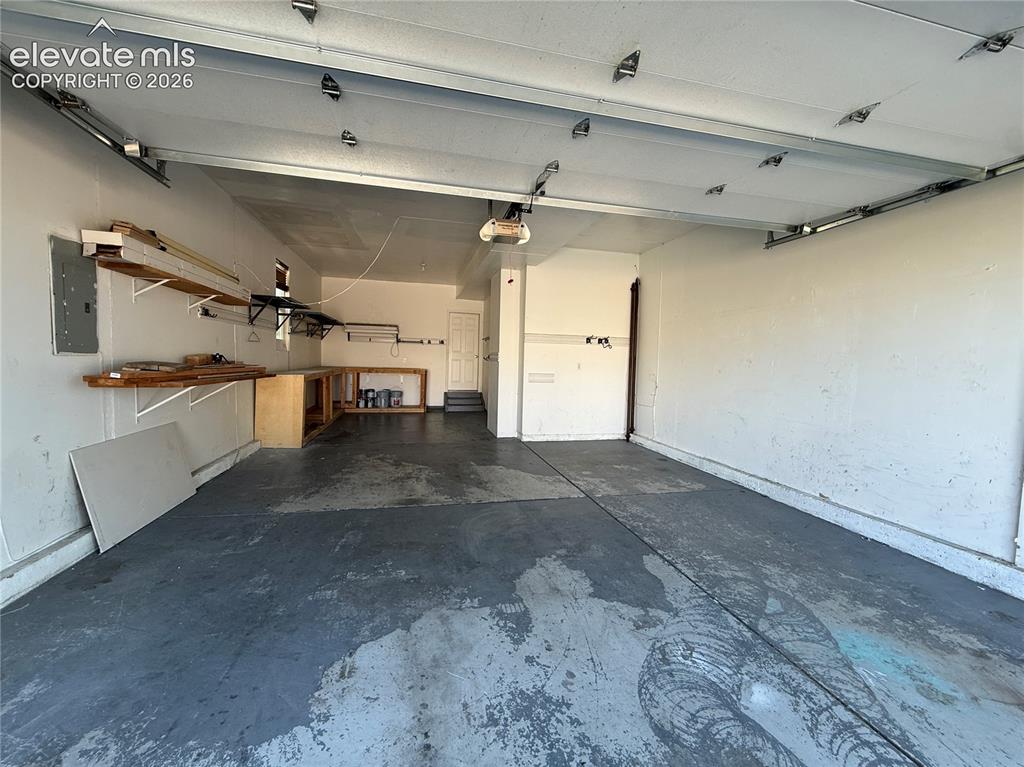 Image 24 of 28: Attached garage featuring an automatic opener, built-in shelving, and a wor