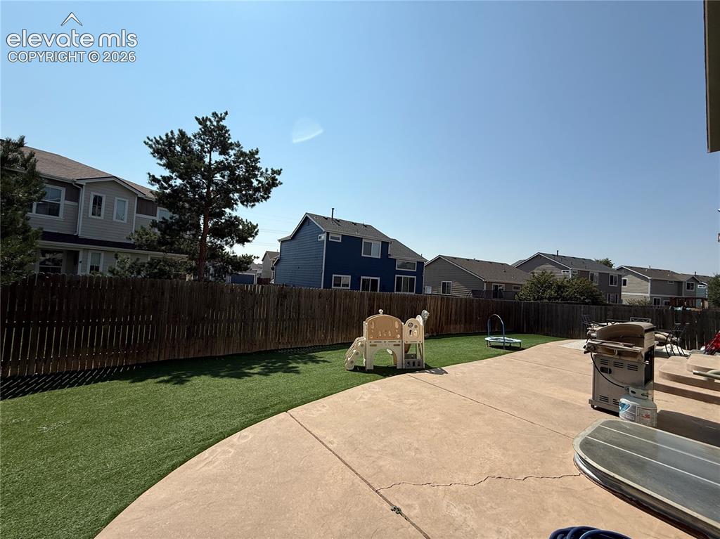 Image 26 of 27: Spacious backyard featuring a concrete patio and a lush green lawn