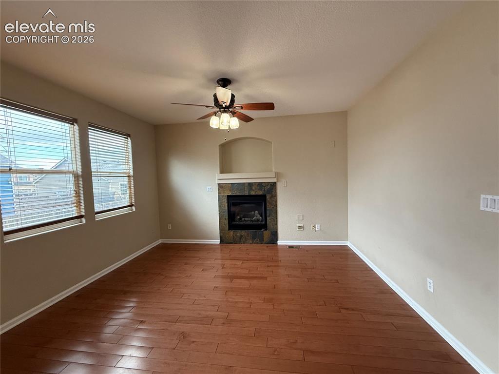 Image 6 of 28: Warm wood-finish flooring, a ceiling fan with integrated lighting, two wind
