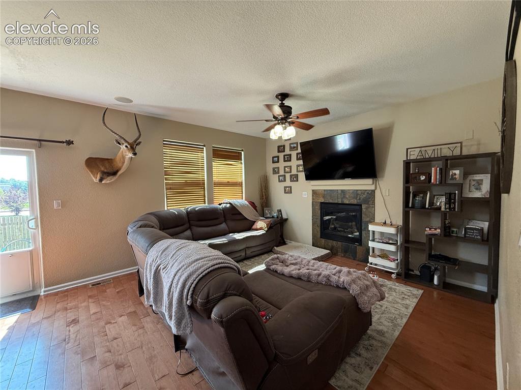 Image 8 of 27: Wood-finish flooring throughout, with a built-in fireplace featuring a ston