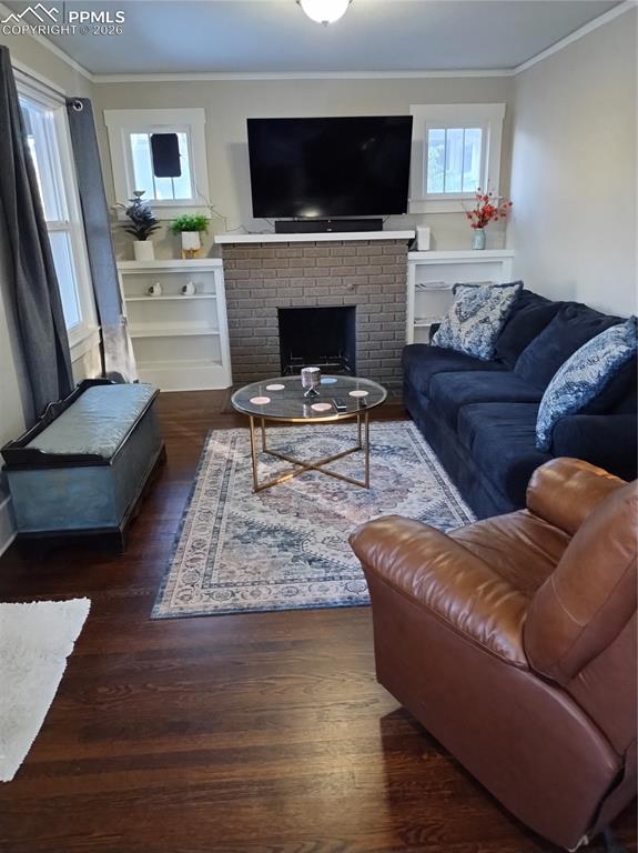 Image 16 of 30: Living room with crown molding, a fireplace, and dark wood-type flooring