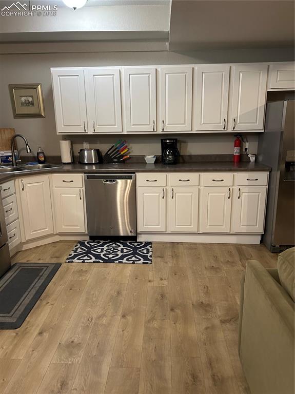 Image 24 of 30: Lower level 
Kitchen featuring dark countertops, white cabinetry, stainles