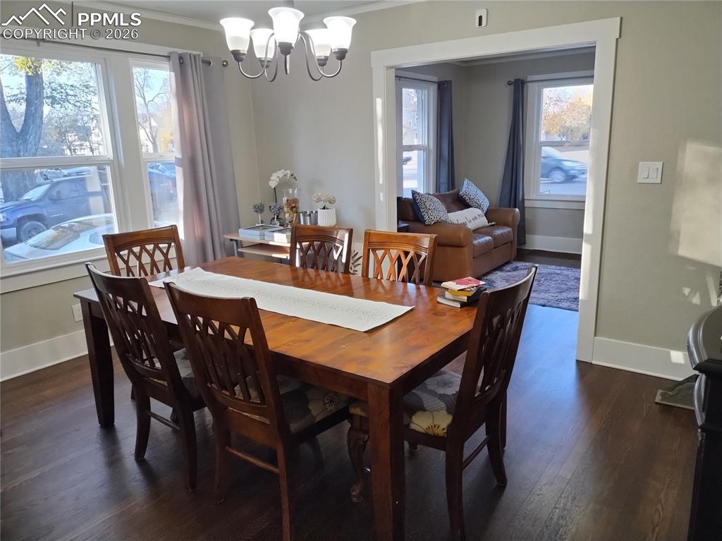 Image 8 of 30: Dining area with hardwood
 flooring, ornamental molding, and a chandelier