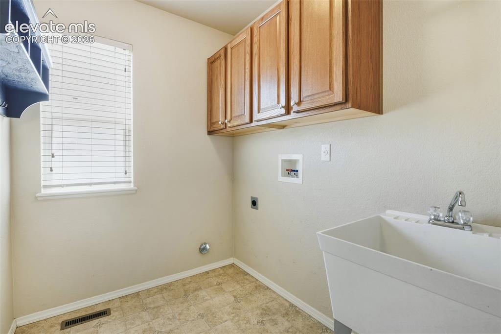 Image 17 of 34: Main level laundry with window, built-ins and utility sink