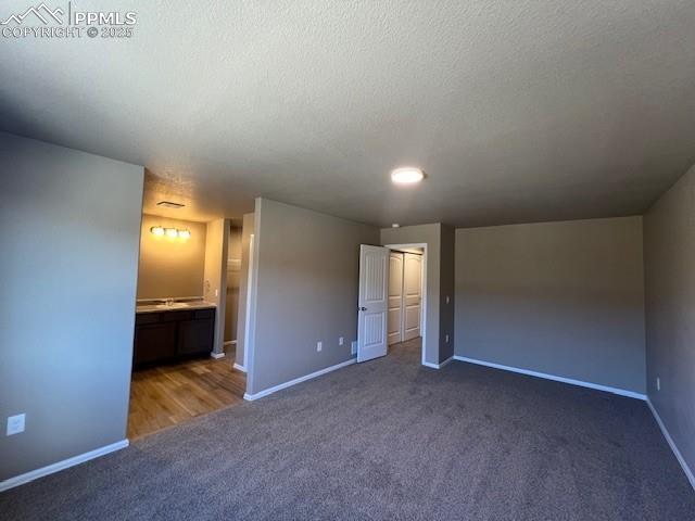 Image 10 of 22: Unfurnished bedroom with ensuite bath, a textured ceiling, and dark colored