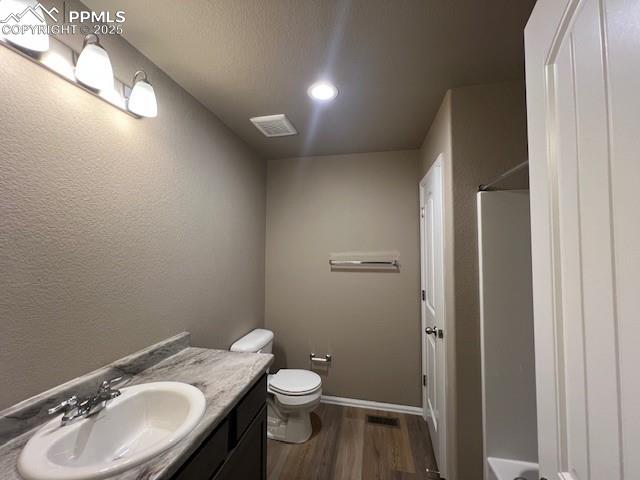 Image 17 of 22: Bathroom featuring hardwood / wood-style floors, vanity, toilet, and a show