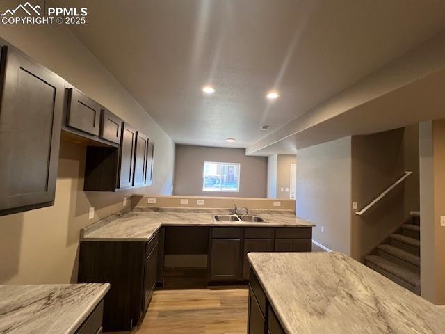 Image 5 of 22: Kitchen with kitchen peninsula, dark brown cabinetry, light hardwood / wood