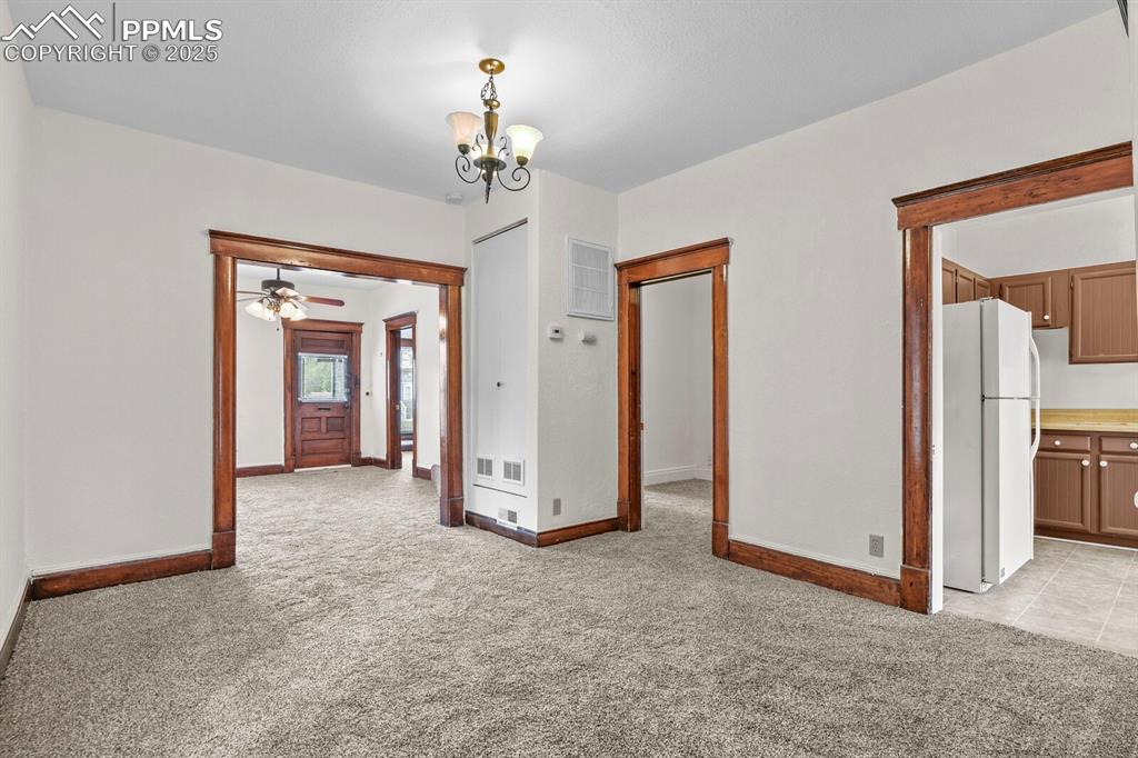Image 23 of 30: Spare room featuring light colored carpet, a chandelier, and ceiling fan