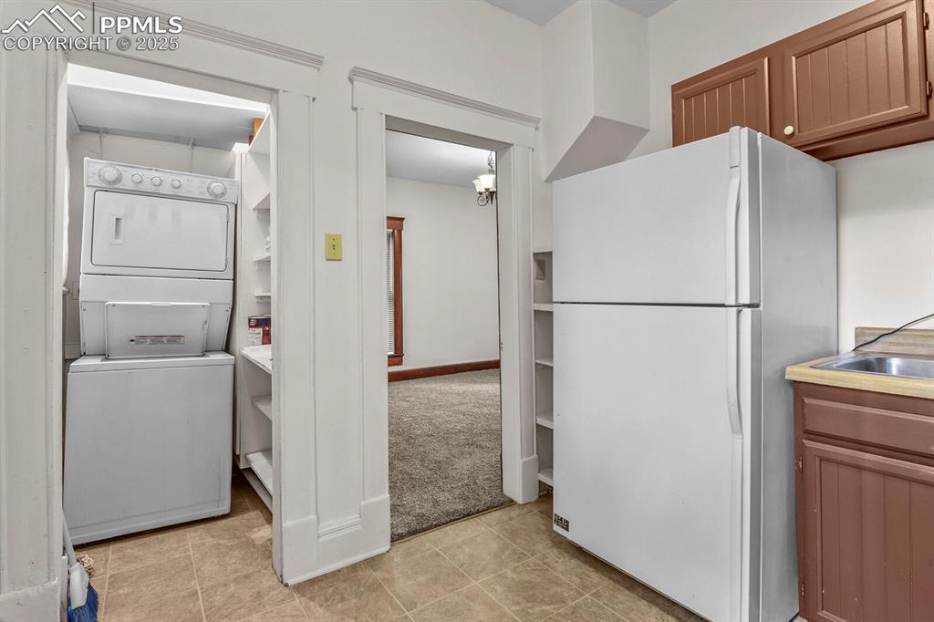 Image 25 of 30: Kitchen featuring freestanding refrigerator, stacked washer / dryer, light
