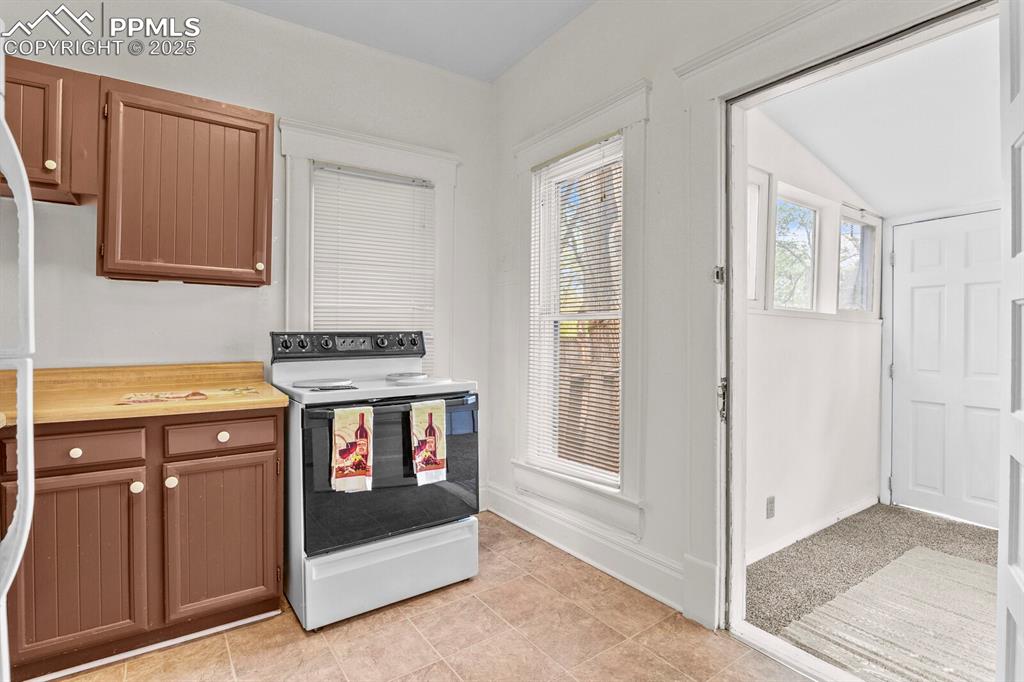 Image 26 of 30: Kitchen with white appliances, butcher block countertops, light tile patter