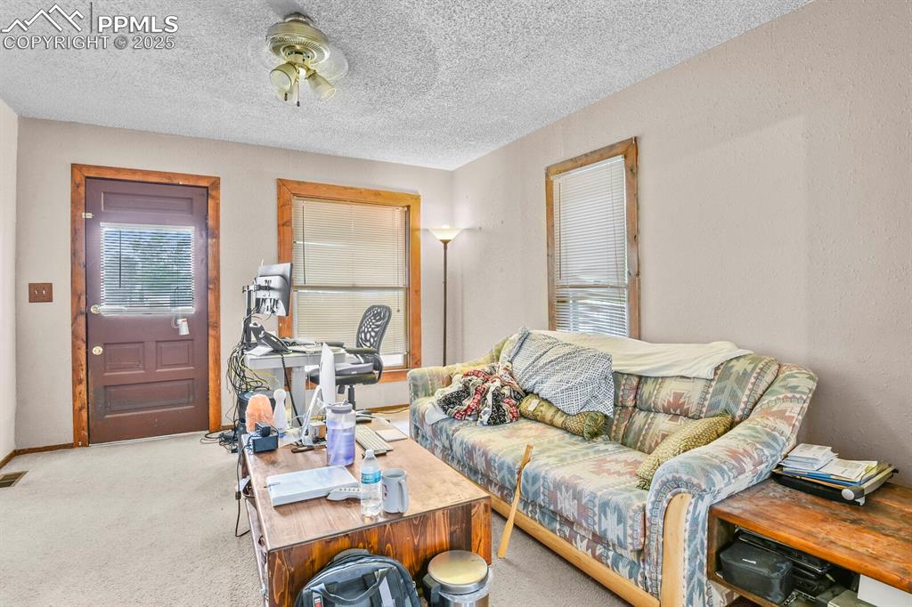 Image 3 of 30: Carpeted living area featuring a textured ceiling and baseboards