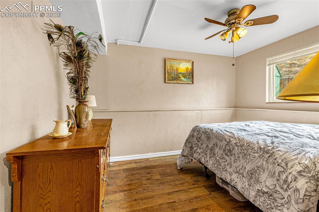 Image 15 of 29: Bedroom featuring dark wood-style floors, ceiling fan, and a textured wall